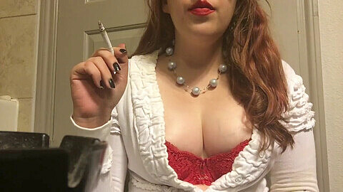 Rauchende Göttin präsentiert ihre riesigen aufgeblähten Brüste in rotem BH und Pullover