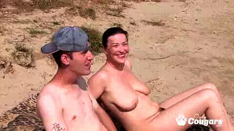 Mamma formosa si diverte con due ragazzi su una spiaggia nudista