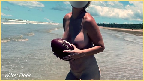 Una esposa traviesa se desnuda y se divierte con un balón de fútbol en la playa