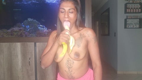 Une amatrice de banane caresse ses seins tout en suçant et en pratiquant une gorge profonde avec une banane