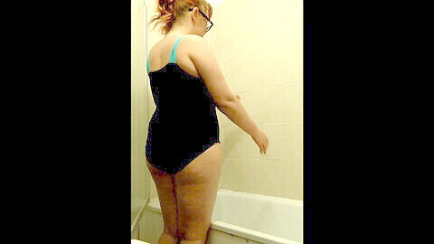 Belle ronde Penny Banks prend une douche mouillée et brillante dans son maillot de bain ébène serré