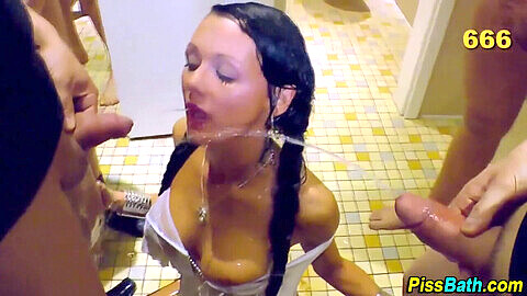Ragazza giovane beve pipì durante un bizzarro bagno dorato di gruppo